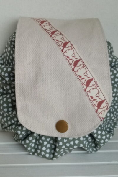 Bourse à maquillage ou à bijoux tout en coton. Forme ronde, se ferme avec un ruban et une languette pressionnée. Motifs tissu extérieur mini cœurs crèmes sur fonc kaki, intérieur kaki, languette écrue - Cherchez le Chas