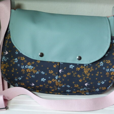 Je, tu , elle, sac en bandoulière. Extérieur mixte en simili cuir et coton avec une double poche à soufflet, intérieur tout coton avec 1 poche. Bandoulière en coton réglable.. Fermeture par 2 pressions métalliques. Simili cuir vert amande, coton gris anthracite motif oiseaux et fleurs, sangle rose pale. cherchez le Chas.